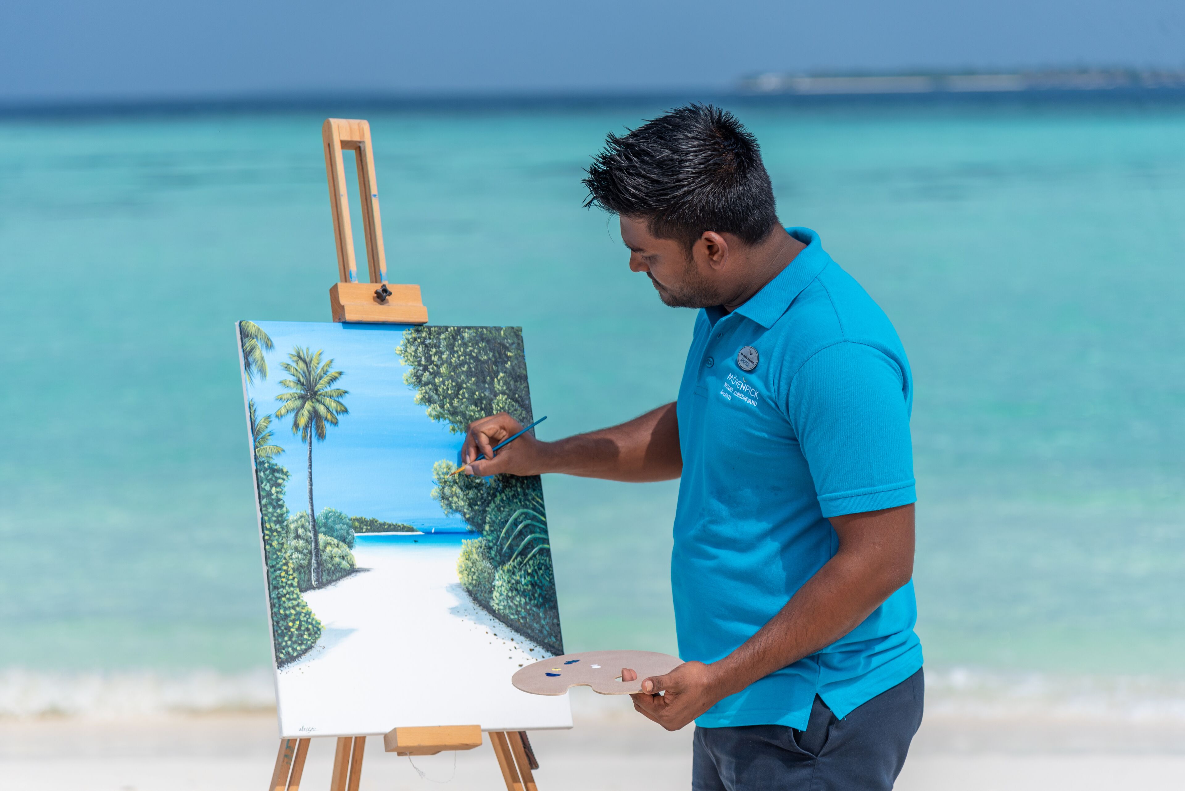 A person painting a beach scene on an easel.