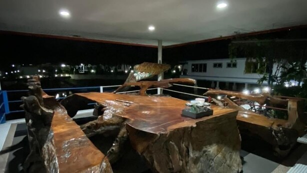Un comedor con una mesa y sillas de madera, suelo de baldosas y vistas de la ciudad de noche.