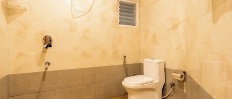 A bathroom with a toilet, shower, and a towel hanging on the wall.