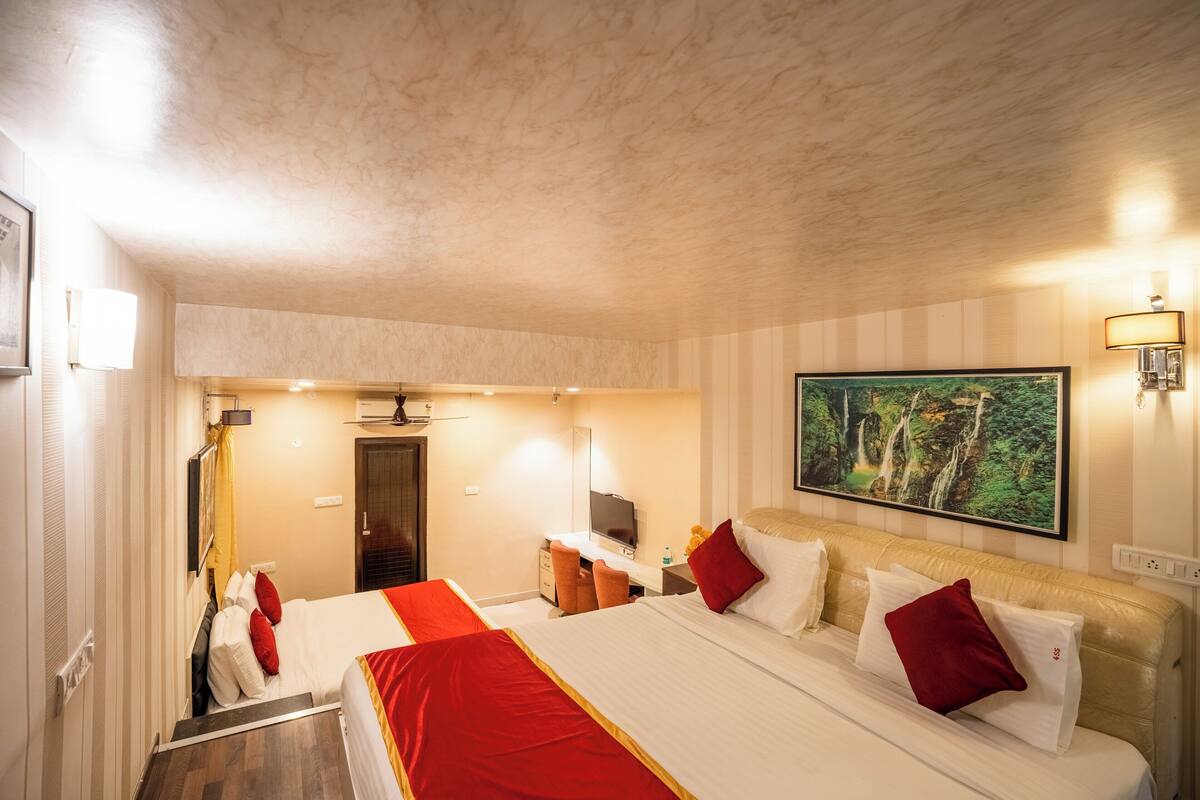 A hotel room with two beds, a TV, a desk, and a painting on the wall.
