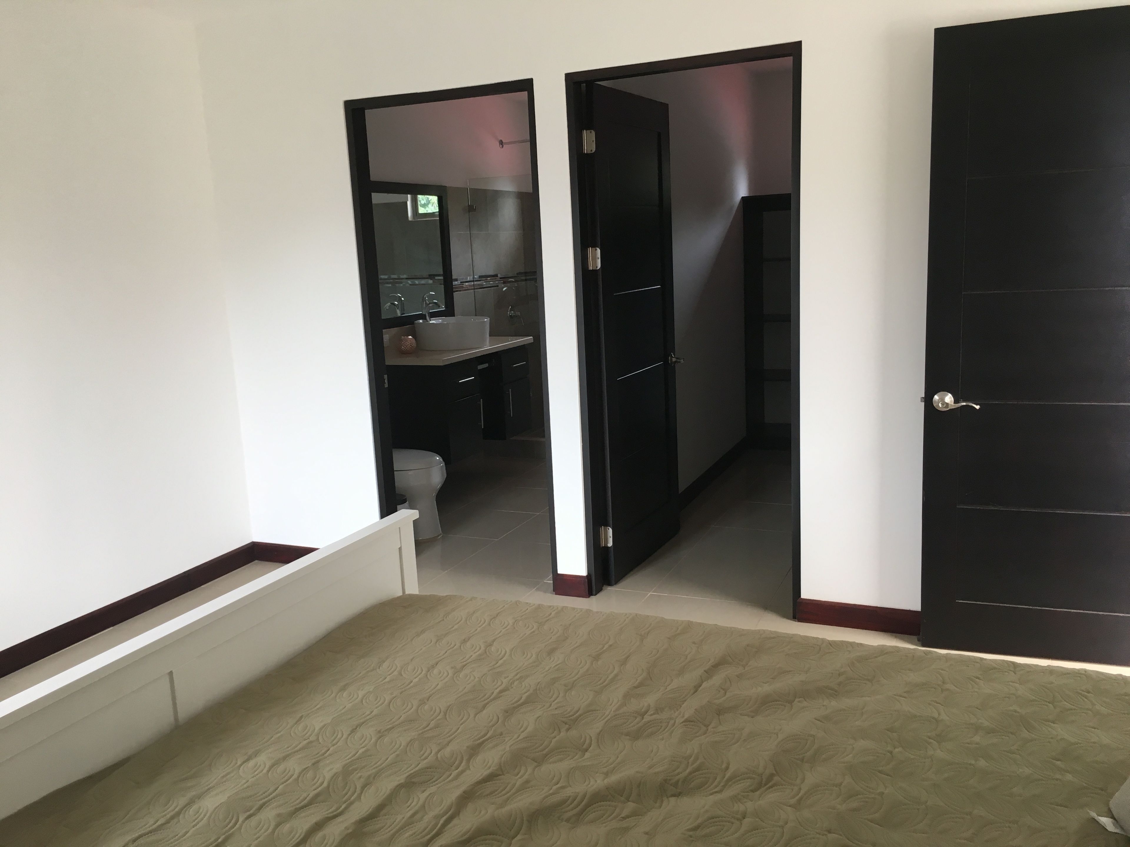 A bedroom with a bed, a door leading to a bathroom, and a view of the bathroom.