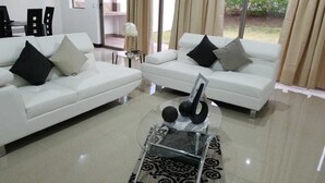 A modern living room with two white sofas, a glass coffee table, and a patterned rug. - Las Yagrumas Condo Escazu (San Rafael)