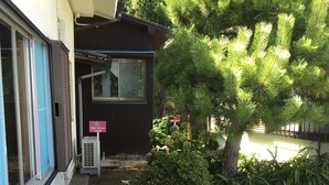 A building with a stone pathway leading to a door, surrounded by greenery and a tree. - Japan Countryside Atami (Atami)