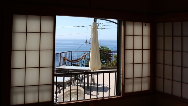 A room with tatami mat flooring, a view of the sea, and a hammock on the balcony. - Japan Countryside Atami (Atami)