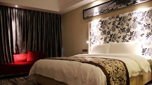 A hotel room with a large bed, a red sofa, and a floral-patterned headboard.