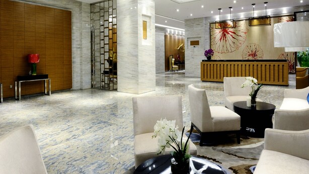 A modern lobby with marble flooring, a reception desk, and seating areas.