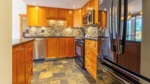 A modern kitchen with wooden cabinets, a stainless steel refrigerator, a microwave, and a dishwasher.