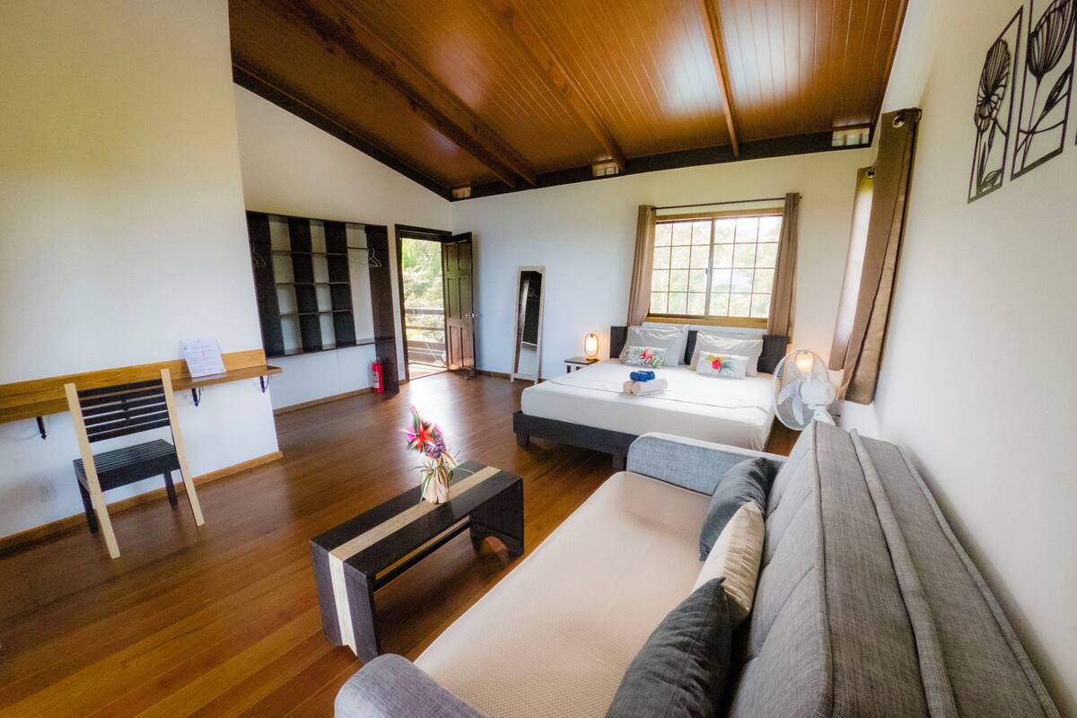 Un salón amplio con una cama grande, un sofá, una mesita de centro y una banca.