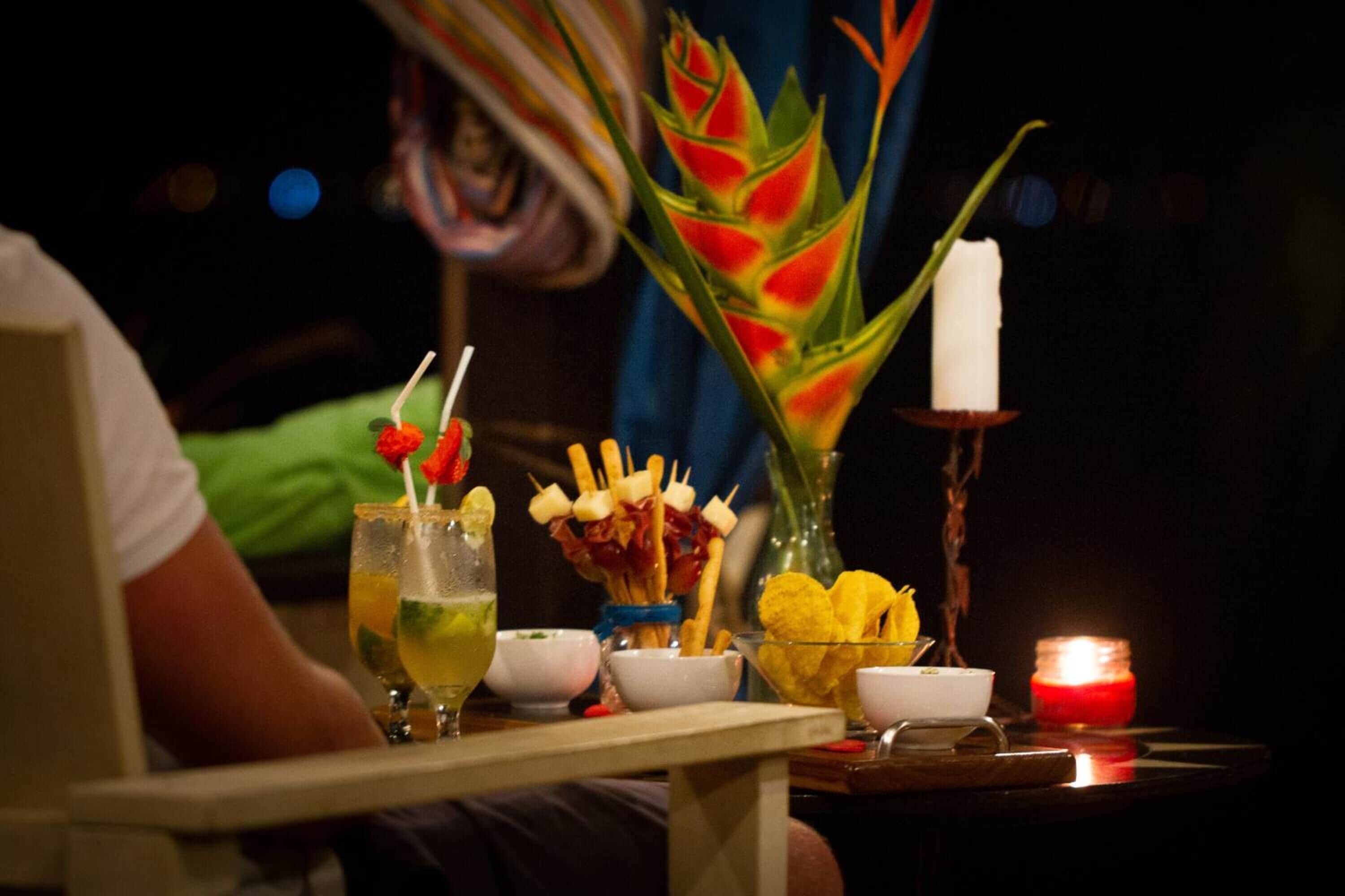A table with a drink, snacks, and a candle.