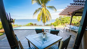 A wooden deck with a pool, a palm tree, and a view of the ocean. - El Caribeo - Nature Lodge (Tierra Oscura)