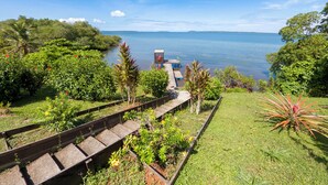 A garden with a wooden deck overlooking a lake. - El Caribeo - Nature Lodge (Tierra Oscura)