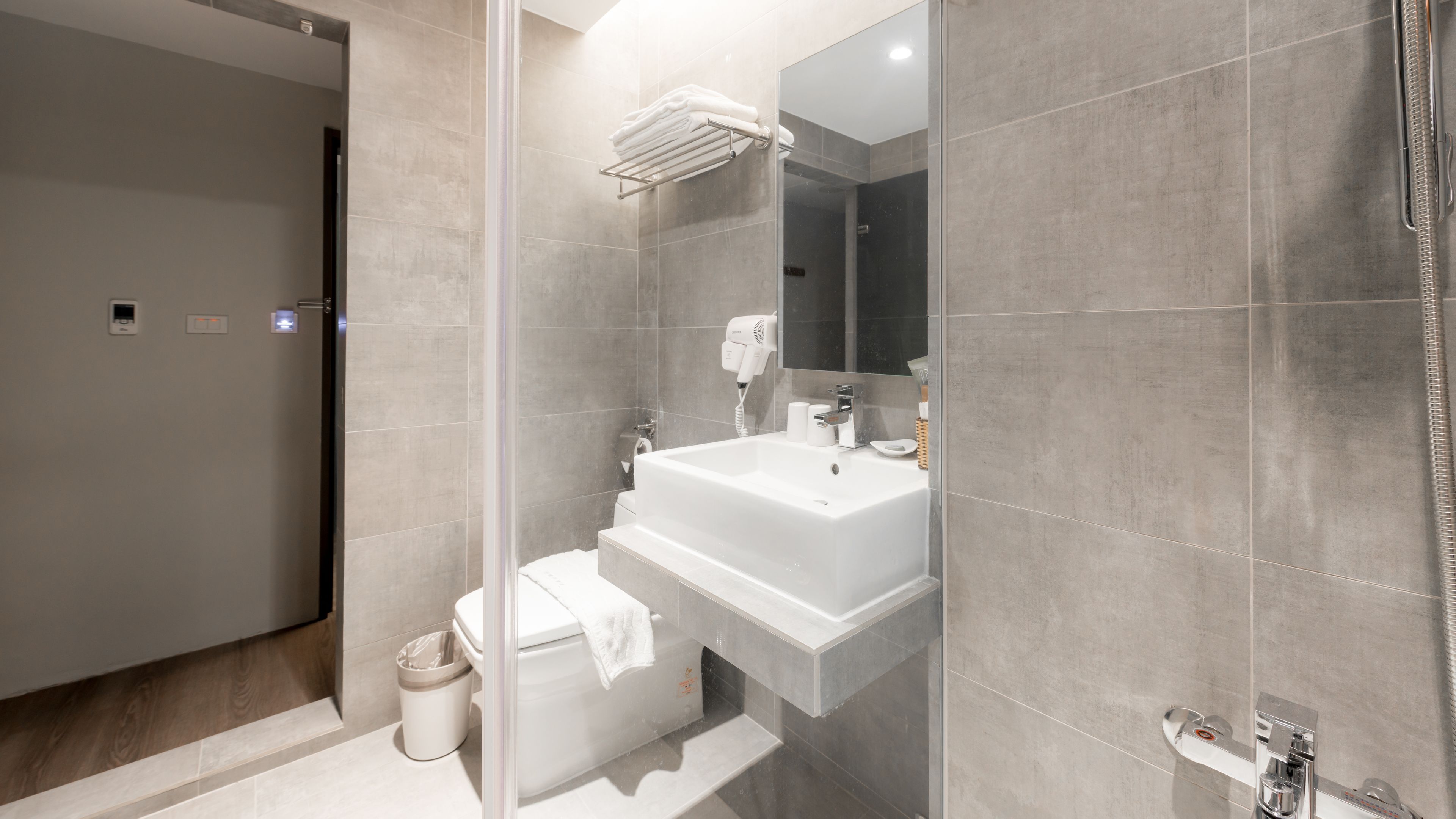 A modern bathroom with a large sink, a toilet, a shower, and a towel rack.