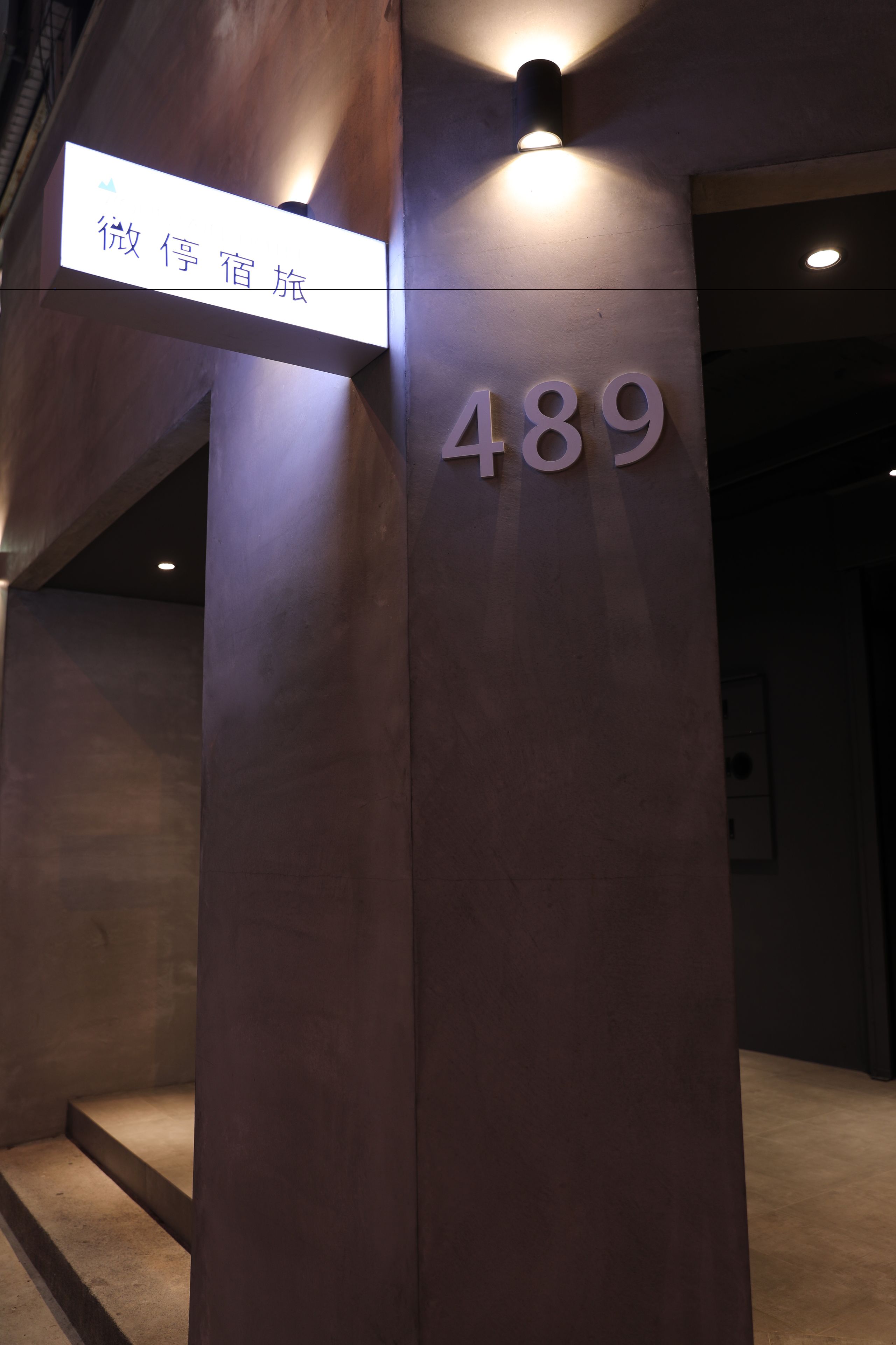 Un pilier d’hôtel portant une plaque indiquant le numéro de chambre 489, et un panneau de signalisation au-dessus.