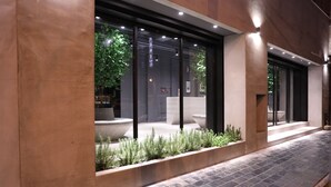 A modern building exterior with large windows, a stone pathway, and a planter with greenery. - Wountain hotel (Hualien City)