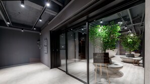 An interior space with glass walls, a modern design, and a seating area with a plant. - Wountain hotel (Hualien City)