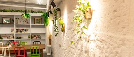 Un rincón comedor acogedor con una mesa de madera, sillas coloridas y una pared blanca con textura decorada con plantas colgantes.