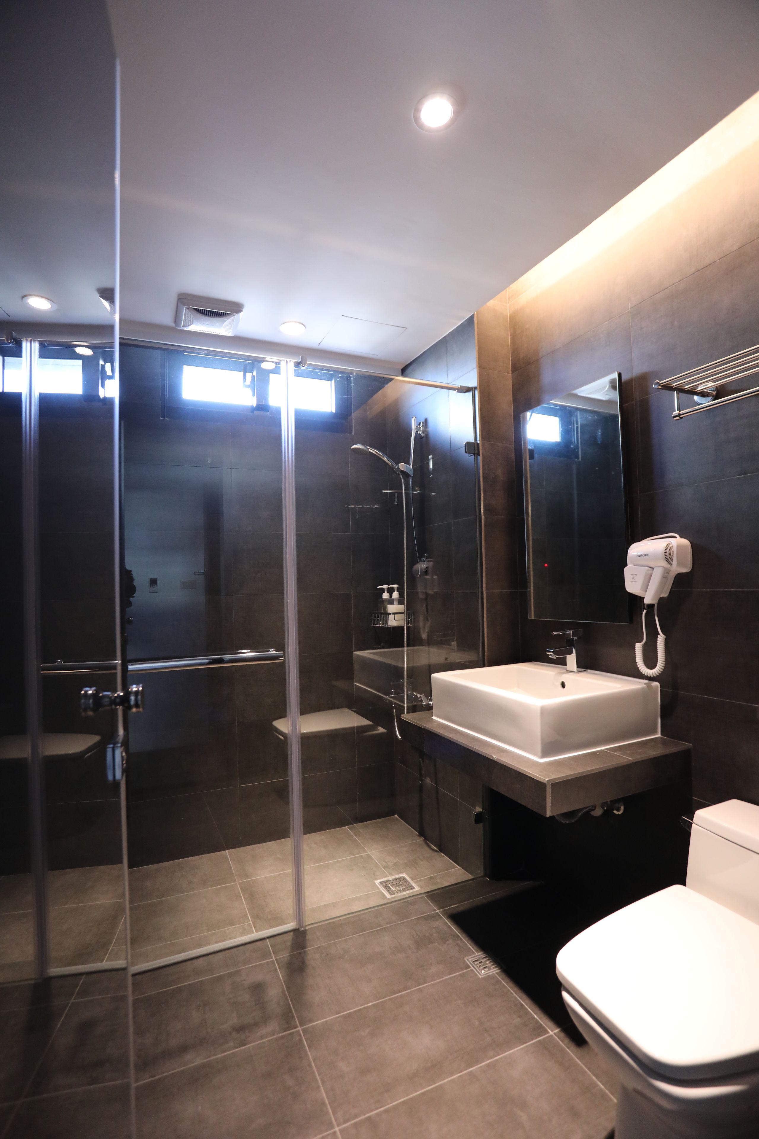 A modern bathroom with a glass-enclosed shower, a white sink, and a toilet.