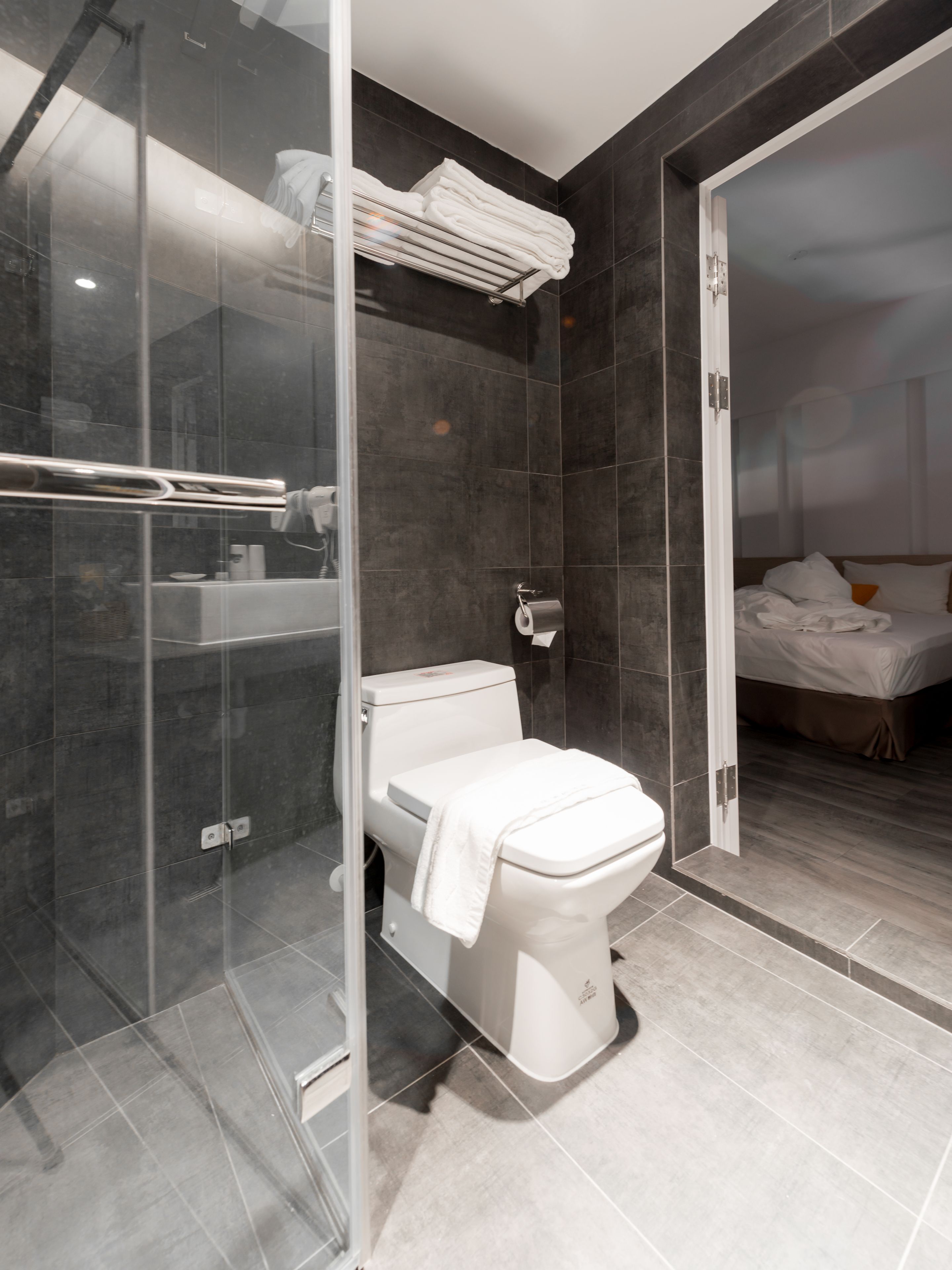 A modern bathroom with a glass-enclosed shower, a white toilet, and a neatly arranged towel rack.