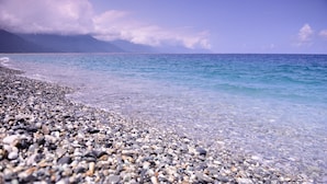A pebbled beach with clear water and distant mountains. - Wountain hotel (Hualien City)