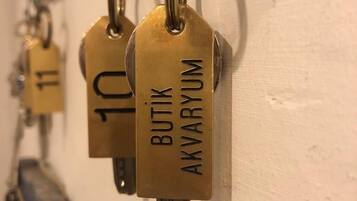 Een rij koperen sleutelhangers met nummers en namen aan een muur.