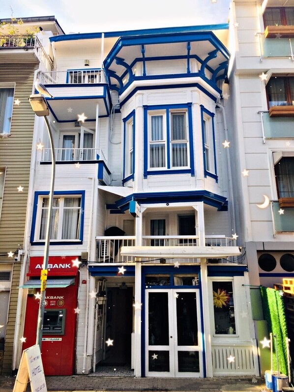 A corner building with a blue and white facade, a visible ATM, and a sign for a hotel. - Butik Akvaryum (Adalar)