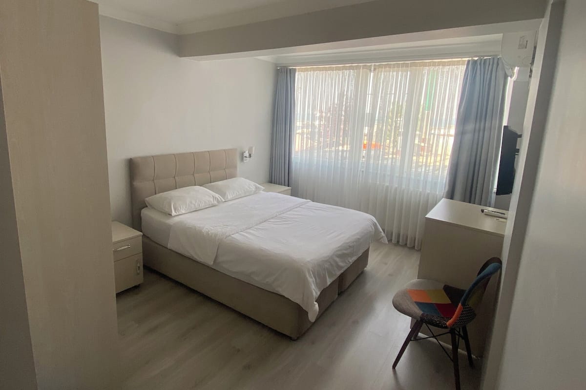 A bedroom with a bed, a desk, and a chair.