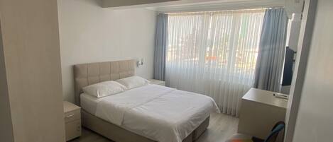A bedroom with a bed, a desk, and a chair.