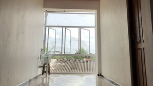 Una habitación amplia con techo alto, ventana grande y puerta.