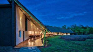 A modern building with a long corridor leading to a dining area, surrounded by natural landscape. - Red Earth Tadoba (Chandrapur)