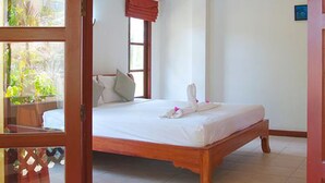 Une chambre avec un lit en bois, une fenêtre avec des rideaux et une vue sur la verdure.
