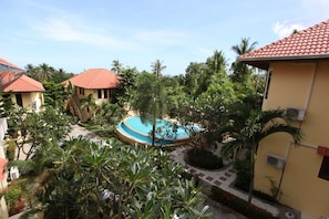 A resort with a central swimming pool surrounded by palm trees and a few buildings with red-tiled roofs. - Samui Green Life (Koh Samui)