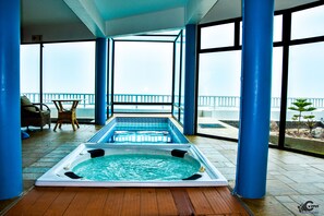 A hot tub on a wooden deck with a view of the sea.