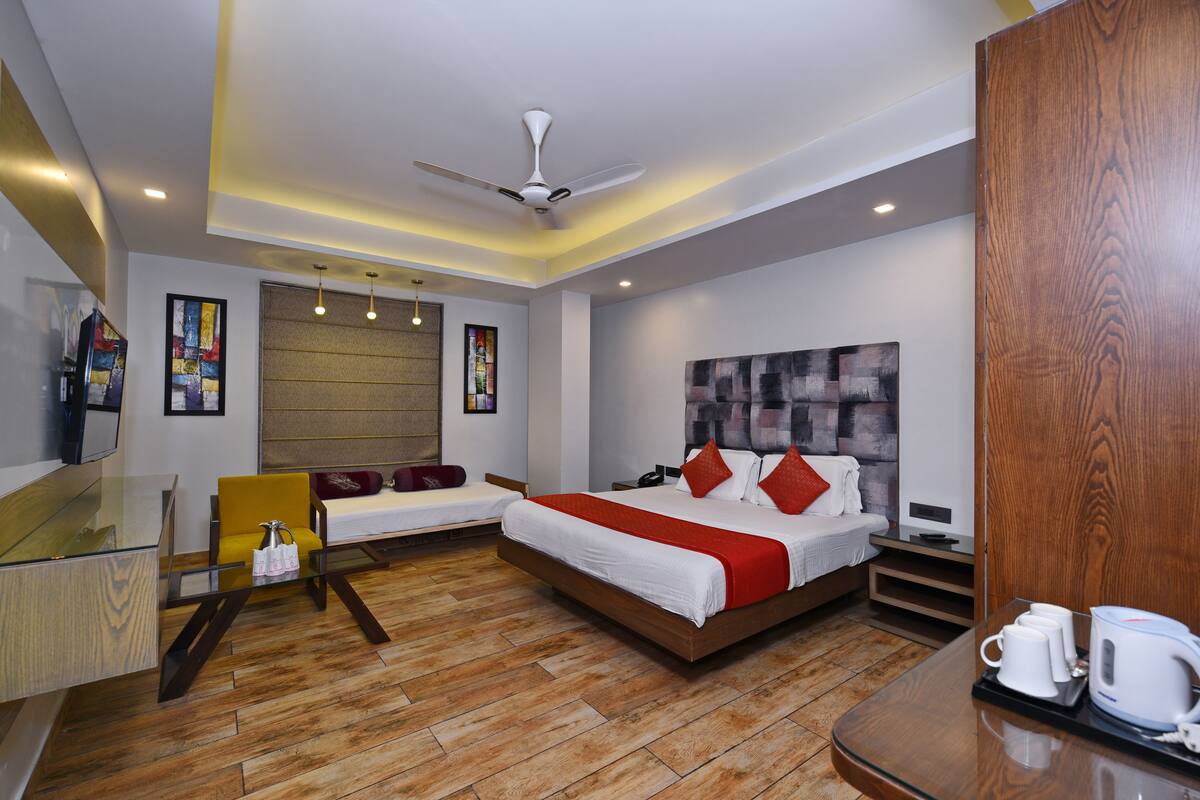 A modern hotel room with a bed, bedside table, and a seating area with a chair.