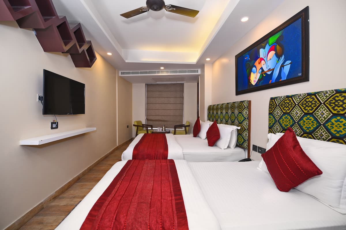 A hotel room with two beds, a flat-screen TV, a ceiling fan, and a painting on the wall.