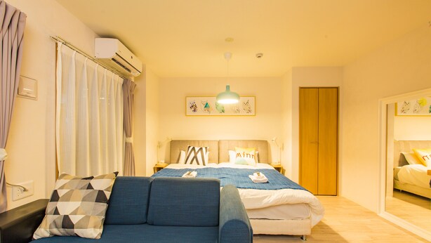 A hotel room with two beds, a sofa, an air conditioning unit, and a framed picture on the wall. - Skyliving Namba (Osaka)