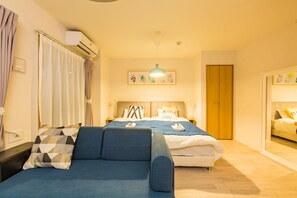 A hotel room with two beds, a sofa, an air conditioning unit, and a framed picture on the wall. - Skyliving Namba (Osaka)