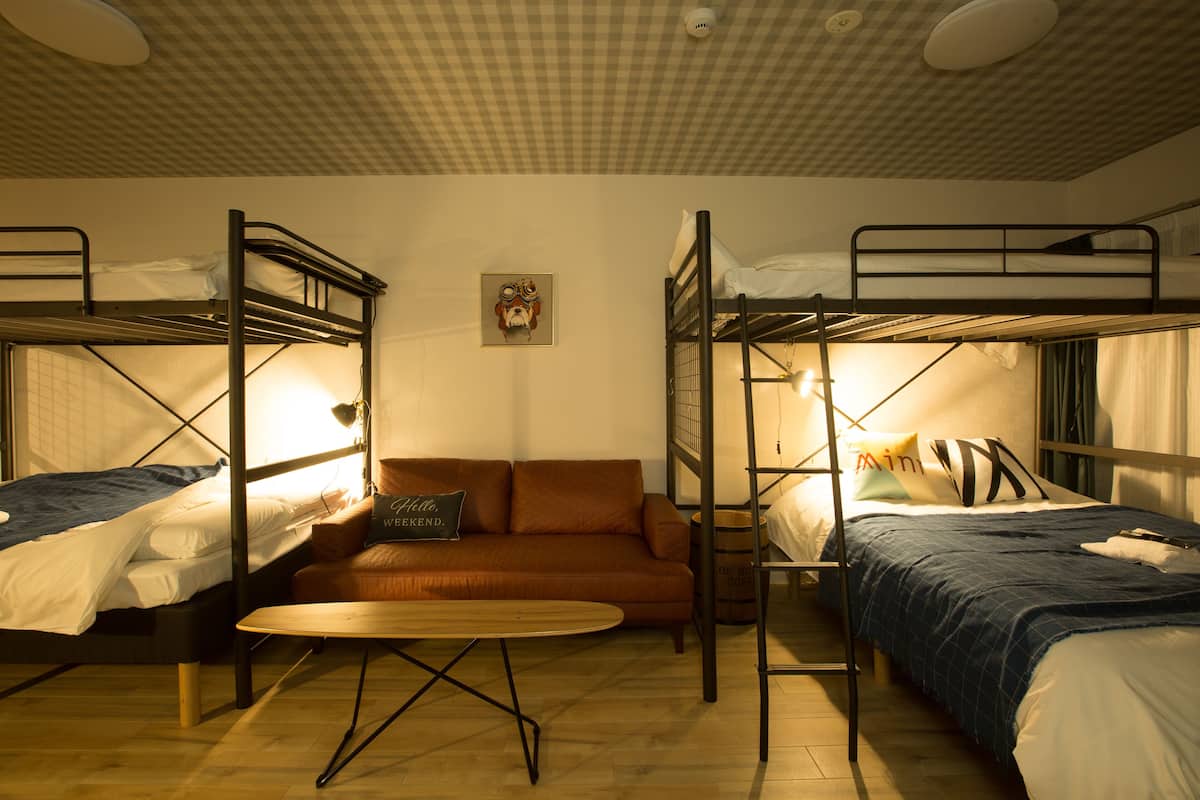 A dormitory room with bunk beds, a sofa, and a small table.
