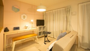 A cozy living room with a sofa, a bench, a TV, a desk with a lamp, and a ceiling light. - Skyliving Namba (Osaka)