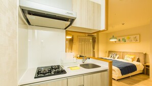 A compact kitchen with a gas stove, sink, and a small countertop. - Skyliving Namba (Osaka)