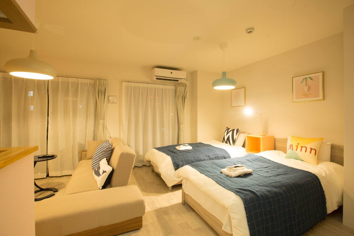 A hotel room with two beds, a sofa, a small table, and a desk.