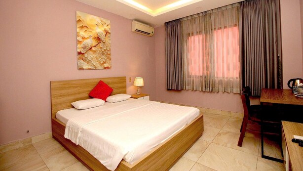 Hotelkamer met een bed, bureau, stoel, airconditioning en een raam met gordijnen.