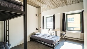 A room with a bunk bed, a desk, a chair, and a window with curtains.