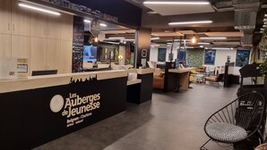 A modern reception area with a black and white color scheme, featuring a logo for 'Les Auberges de Jeunesse' in Belgium.