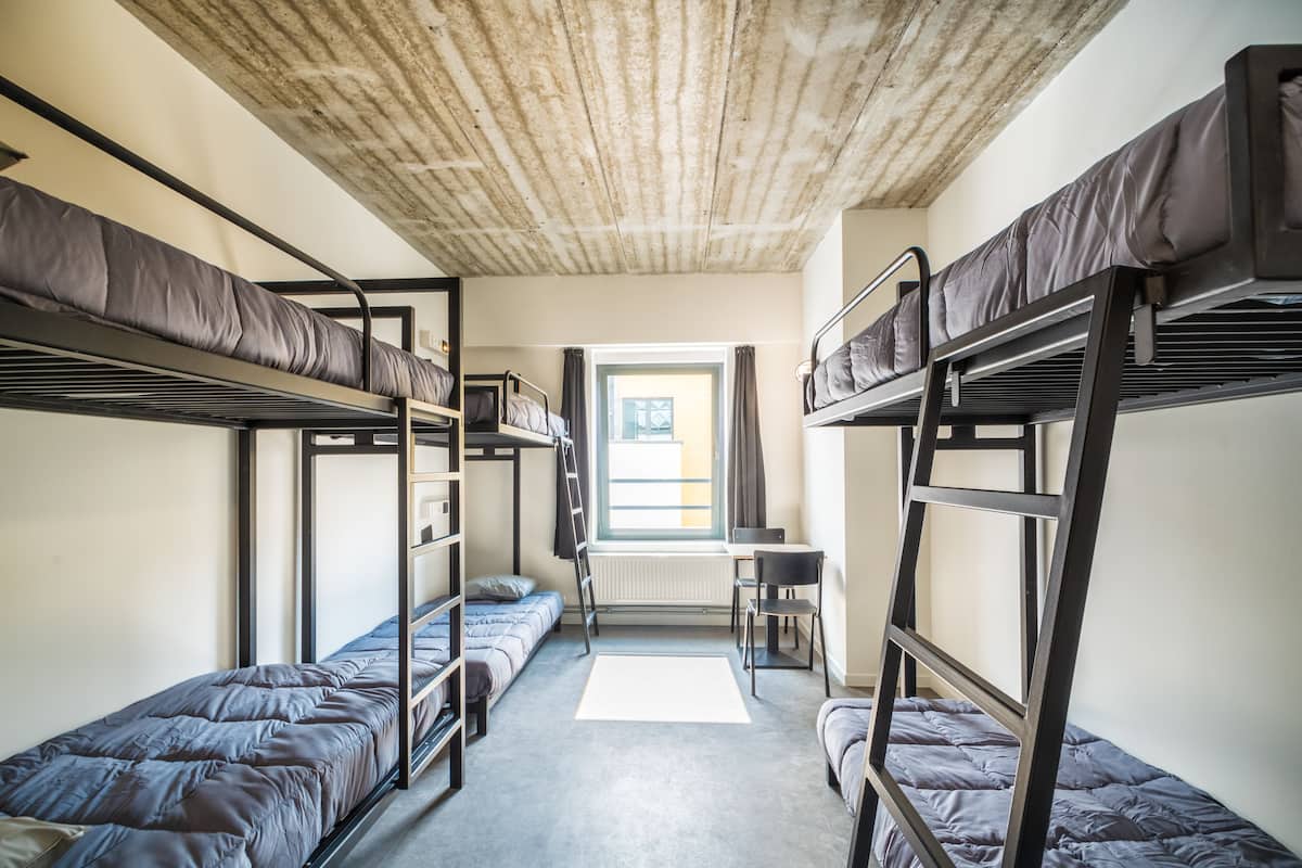 Asuntolan huone, jossa on kerrossängyt, työpöytä ja ikkuna, jossa on verhot.