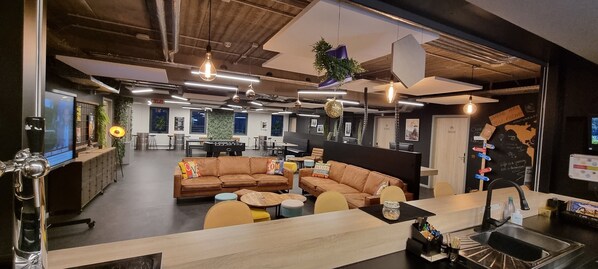 An open-plan office with a central seating area, a kitchen counter, and a visible restroom.
