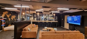 Een moderne lounge met een bar, banken en een televisie waarop een kaart wordt getoond.