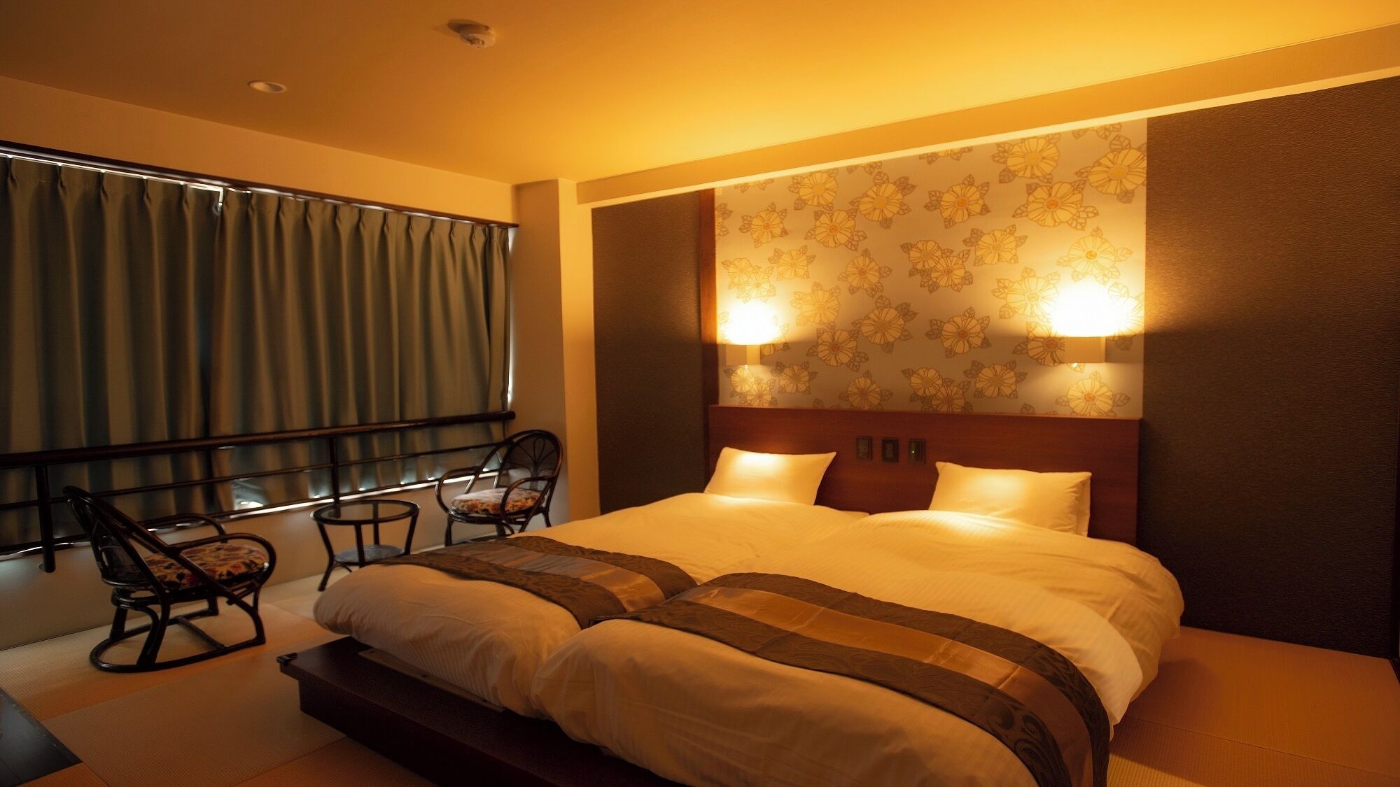 A hotel room with a large bed, two bedside lamps, a chair, and a window with curtains.