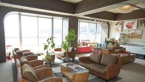 A spacious lobby with wicker furniture, a central glass coffee table, and a view through large windows. - RYUGU no TSUKAI (Higashiizu)