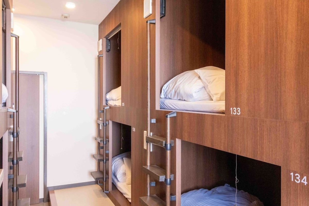 Habitación de hotel con literas, paredes de madera y una puerta visible.