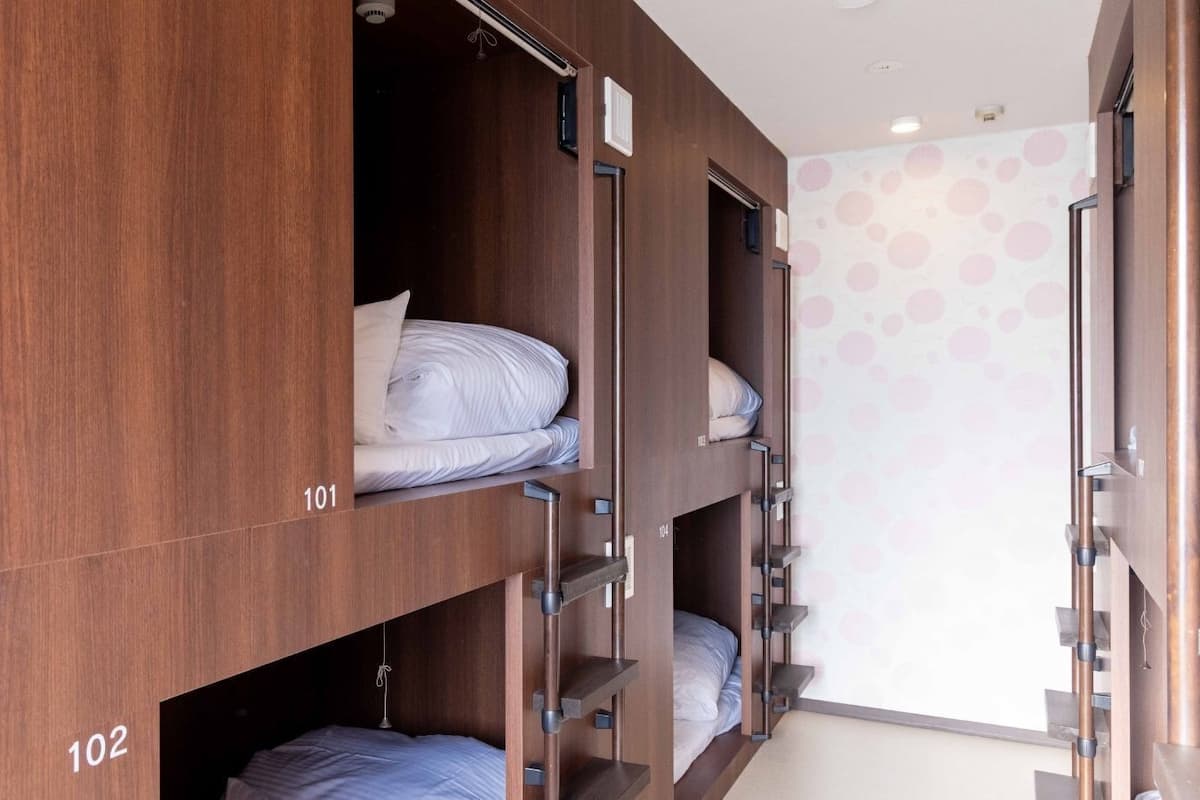 Dormitorio con literas, paredes de madera, camas numeradas y un papel tapiz decorativo.